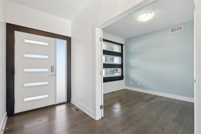 foyer entrance with dark wood-style flooring, visible vents, and baseboards