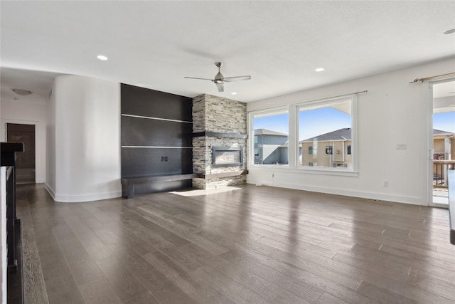 unfurnished living room featuring ceiling fan, a fireplace, wood finished floors, and baseboards