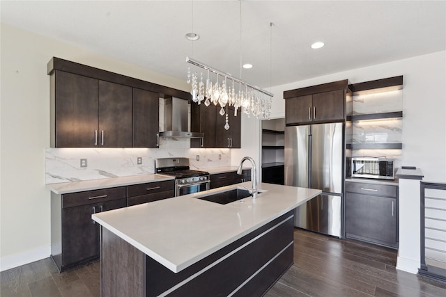 kitchen featuring appliances with stainless steel finishes, a sink, dark brown cabinets, wall chimney range hood, and backsplash