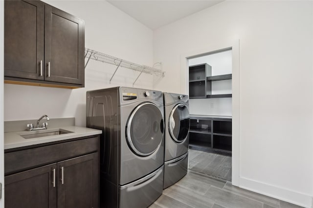 washroom featuring wood tiled floor, cabinet space, a sink, and washer and clothes dryer