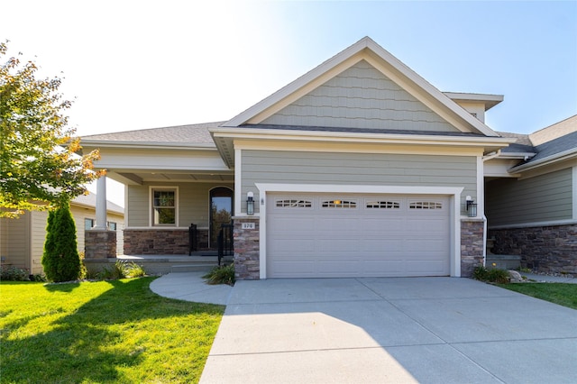 craftsman house with concrete driveway, covered porch, a front yard, a garage, and stone siding