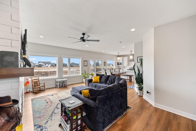 living area with a ceiling fan, recessed lighting, baseboards, and wood finished floors