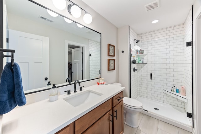 bathroom with a stall shower, visible vents, vanity, and toilet