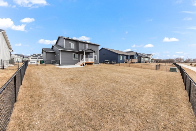 back of house with a fenced backyard, a residential view, and a lawn