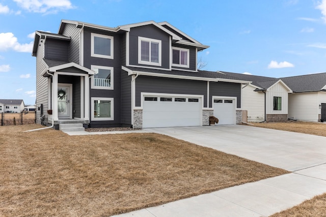 view of front of house with a garage, concrete driveway, stone siding, fence, and a front yard