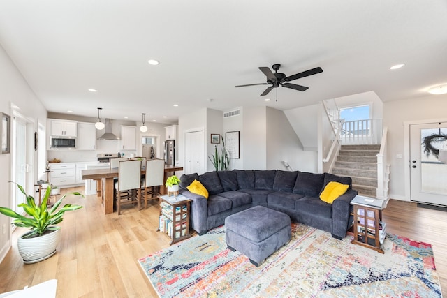 living area with light wood-style flooring, recessed lighting, visible vents, baseboards, and stairs