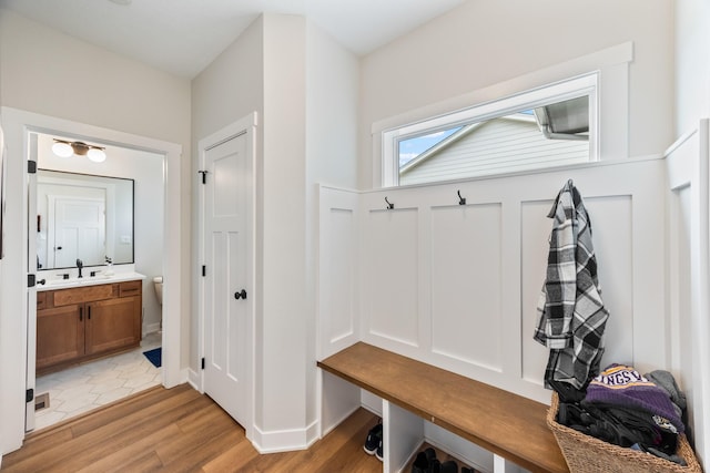 mudroom featuring light wood-type flooring, a sink, and baseboards