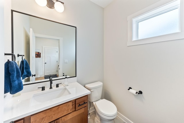 bathroom with baseboards, vanity, and toilet