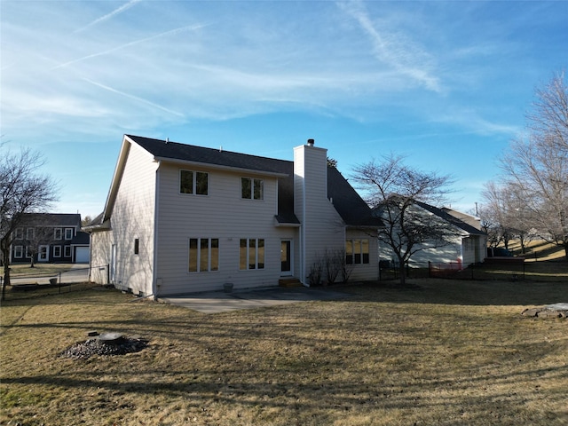 rear view of house featuring a yard, a patio area, and a chimney