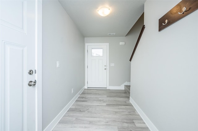 entryway featuring visible vents, light wood finished floors, baseboards, and stairs