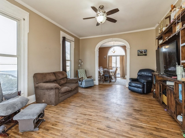 living room with baseboards, ceiling fan, ornamental molding, wood finished floors, and arched walkways