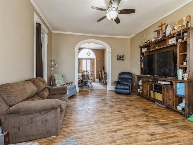 living room featuring arched walkways, ornamental molding, and wood finished floors