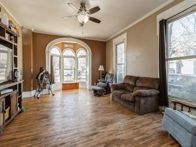 living area with a wealth of natural light, wood finished floors, and crown molding