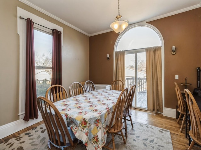 dining area with crown molding, wood finished floors, and baseboards