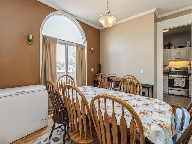 dining area featuring light wood-style floors and ornamental molding