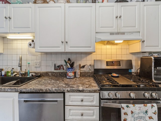 kitchen with a sink, stainless steel appliances, white cabinets, under cabinet range hood, and dark countertops