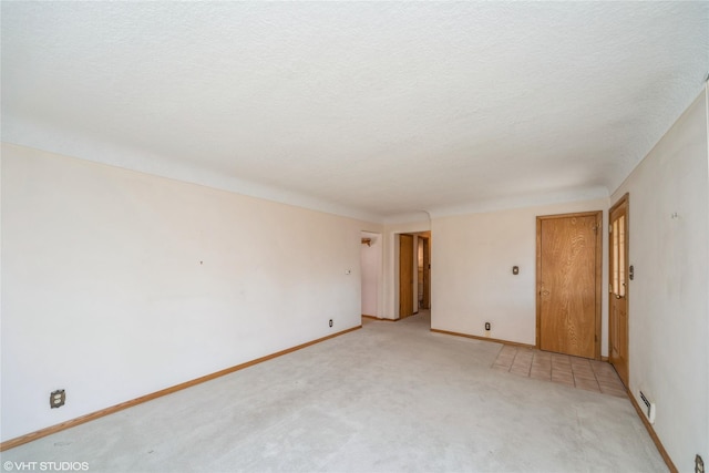 unfurnished room featuring a textured ceiling, baseboards, and light colored carpet