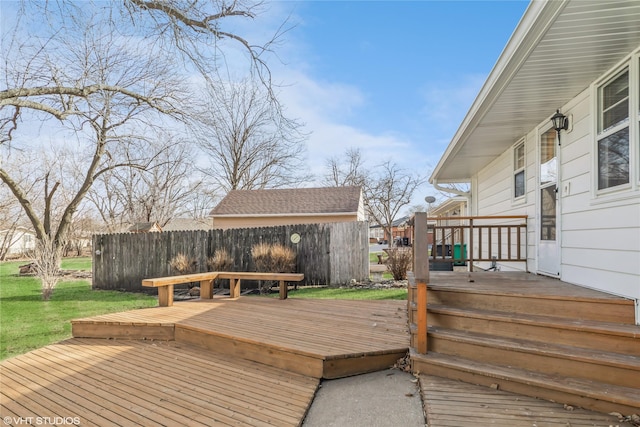 wooden terrace featuring a yard and fence