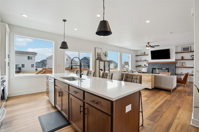 kitchen with light wood-type flooring, a breakfast bar, hanging light fixtures, and a tiled fireplace