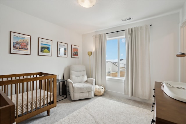 bedroom featuring a nursery area, light carpet, and visible vents