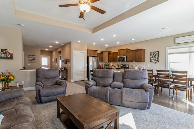 carpeted living room featuring a healthy amount of sunlight, baseboards, a sink, and recessed lighting