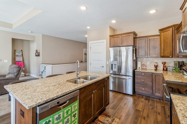 kitchen with decorative backsplash, dark wood-style floors, open floor plan, stainless steel appliances, and a sink