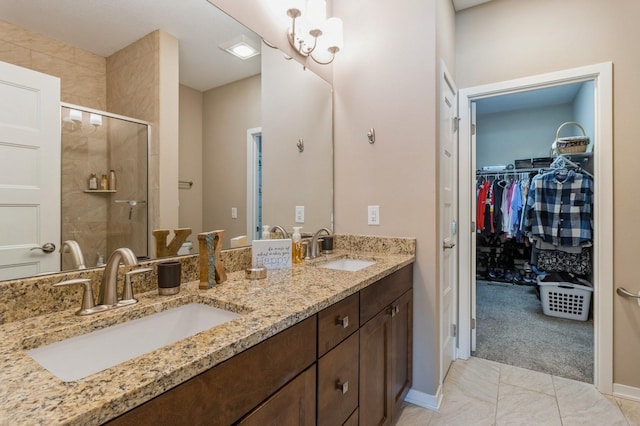 bathroom with a spacious closet, double vanity, a sink, and a shower stall