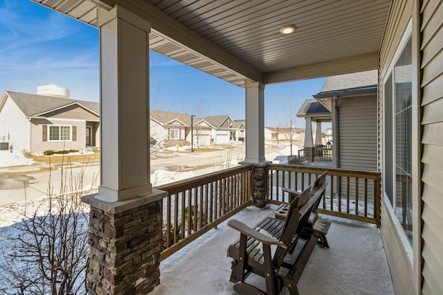 snow covered patio with covered porch and a residential view