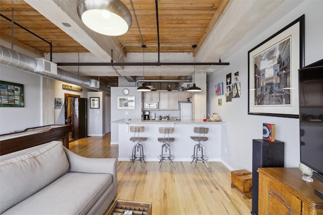 living room with baseboards, light wood-style flooring, visible vents, and beamed ceiling