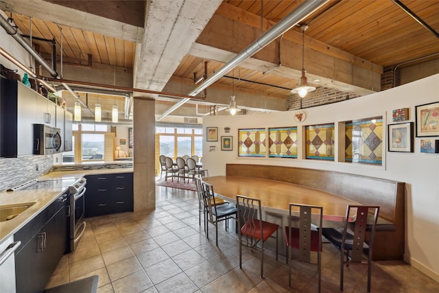 kitchen featuring wood ceiling, stainless steel appliances, dark cabinetry, light countertops, and pendant lighting