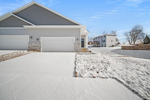 view of front of house with a garage, stone siding, and driveway