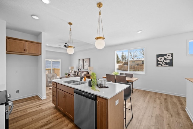 kitchen with stainless steel appliances, brown cabinetry, a sink, and light wood-style flooring