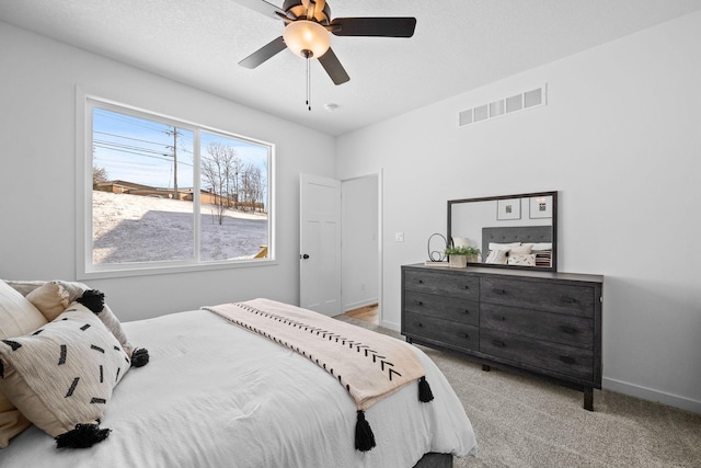 bedroom featuring baseboards, visible vents, a ceiling fan, and light colored carpet