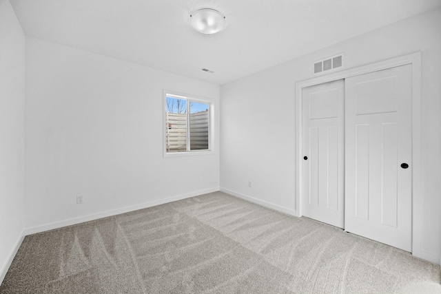 unfurnished bedroom with carpet floors, baseboards, visible vents, and a closet