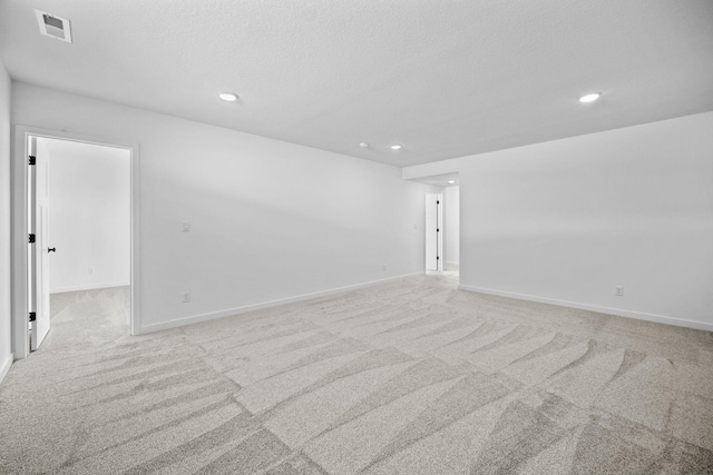 unfurnished room with a textured ceiling, recessed lighting, light carpet, visible vents, and baseboards