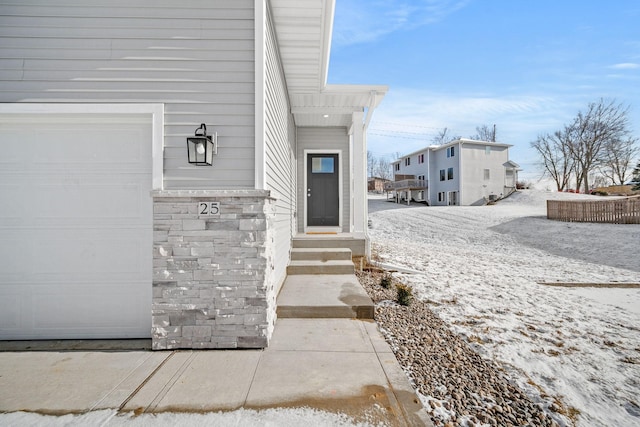 view of exterior entry with a garage and stone siding