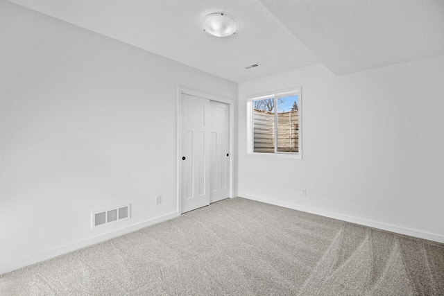 carpeted empty room featuring visible vents and baseboards