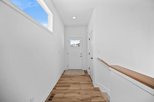 doorway featuring light wood-type flooring, visible vents, and baseboards