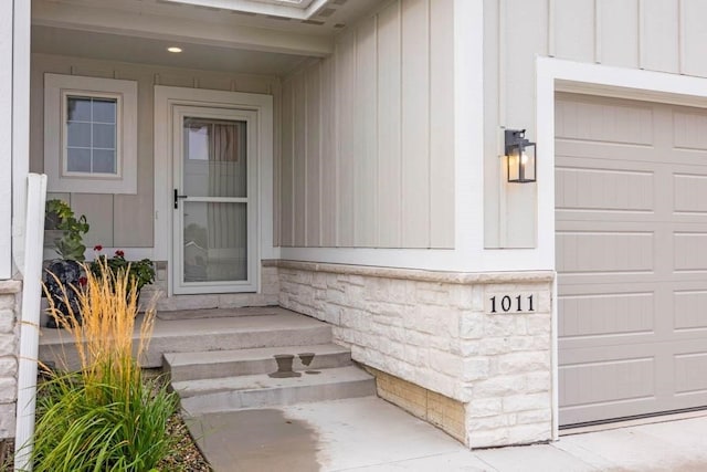 doorway to property featuring a garage, stone siding, and board and batten siding