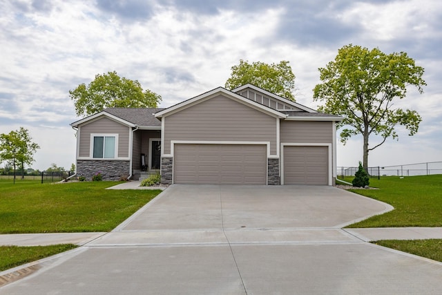 view of front of house with concrete driveway, stone siding, an attached garage, fence, and a front yard