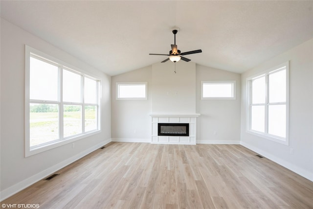 2908 Yordi Dr, Norwalk, IA 50211 - unfurnished living room with ceiling fan, light wood finished floors, a glass covered fireplace, healthy amount of natural light, and lofted ceiling