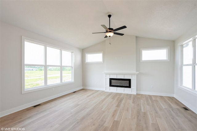 2908 Yordi Dr, Norwalk, IA 50211 - unfurnished living room with light wood-type flooring, lofted ceiling, ceiling fan, a glass covered fireplace, and healthy amount of natural light