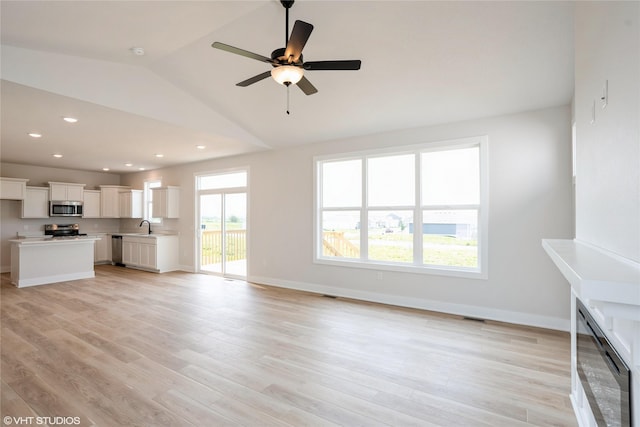 2908 Yordi Dr, Norwalk, IA 50211 - unfurnished living room with a sink, vaulted ceiling, light wood-style flooring, ceiling fan, and baseboards