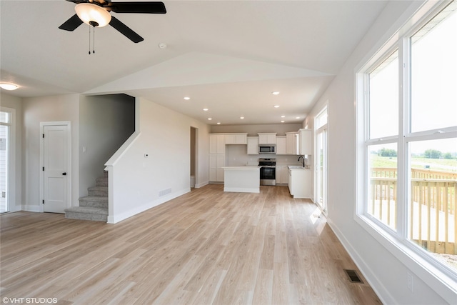 2908 Yordi Dr, Norwalk, IA 50211 - unfurnished living room featuring light wood finished floors, stairway, baseboards, vaulted ceiling, and a sink