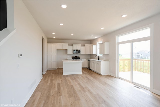 2908 Yordi Dr, Norwalk, IA 50211 - kitchen with appliances with stainless steel finishes, light wood-style flooring, white cabinetry, a sink, and recessed lighting