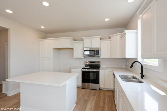 2908 Yordi Dr, Norwalk, IA 50211 - kitchen with stainless steel appliances, a sink, light wood-type flooring, white cabinets, and recessed lighting