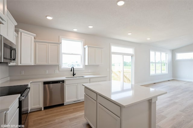 2908 Yordi Dr, Norwalk, IA 50211 - kitchen featuring stainless steel appliances, a sink, light wood-style floors, a kitchen island, and white cabinetry