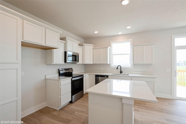 2908 Yordi Dr, Norwalk, IA 50211 - kitchen with appliances with stainless steel finishes, a sink, a kitchen island, light wood-style flooring, and recessed lighting