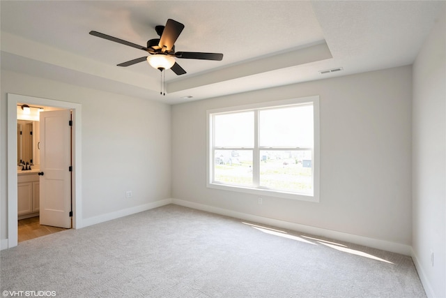 2908 Yordi Dr, Norwalk, IA 50211 - empty room featuring light carpet, baseboards, a tray ceiling, and a ceiling fan