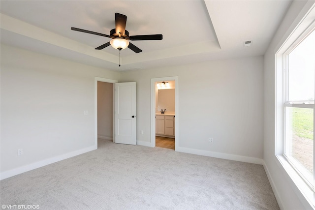 2908 Yordi Dr, Norwalk, IA 50211 - unfurnished bedroom with light colored carpet, baseboards, ensuite bathroom, and a raised ceiling
